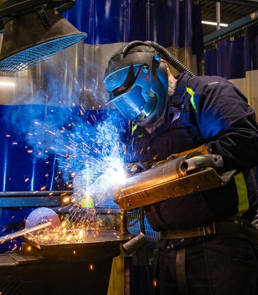 Soldador trabajando con chispas de soldadura sobre una pieza metálica